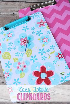 a clipboard with flowers on it next to a pink and blue flowered notebook