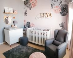 a baby's room decorated in pink and gray with roses on the wall, crib, chair, dresser and mirror