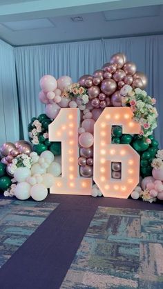 balloons and flowers are arranged in the shape of the number sixteen on display at an event