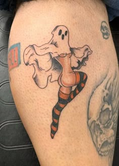 a person with a ghost tattoo on their arm and leg, holding a candy cane