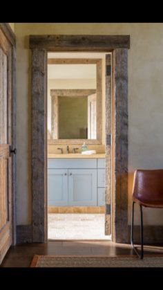 an open door leading to a bathroom with a sink and mirror on the wall next to a chair