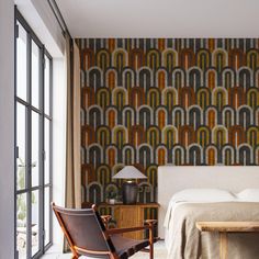 a bed sitting next to a wooden table in a bedroom under a large wallpaper