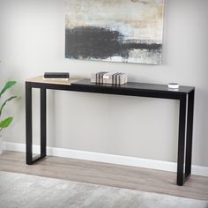 a black console table with two books on it and a plant in the corner next to it