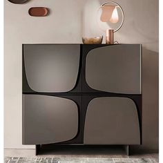 a black and grey cabinet sitting in front of a wall with three mirrors on it