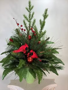 a green vase filled with red flowers and greenery