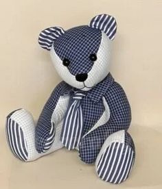 a blue and white teddy bear sitting on top of a table next to a wall