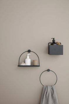 two shelves with soap and lotion on them against a gray wall, one holding a towel