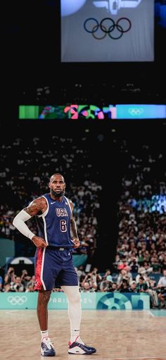 a man standing on top of a basketball court with his hands on his hips in front of an audience