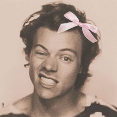 an old black and white photo of a man with a pink bow on his head