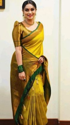 a woman in a yellow and green sari standing next to a painting on the wall