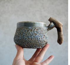 a hand holding a ceramic cup with a handle