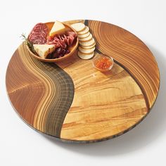 a wooden platter with food on it and crackers in the middle, along with sauces