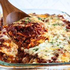 a wooden spoon scooping some lasagna out of the casserole dish