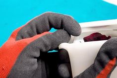 a gloved hand holding an electrical outlet in front of a blue wall and white box