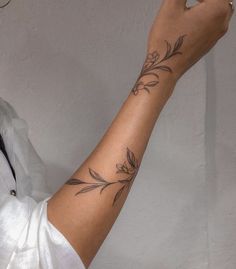 a woman with a flower tattoo on her arm holding up a cell phone to the camera