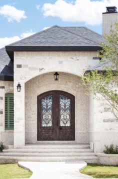 the front entrance to a home with two large doors and steps leading up to it