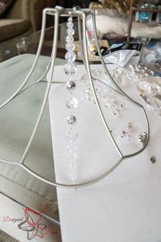 a white table topped with a lamp shade covered in crystal beads and chains on top of it