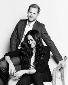 a man and woman are sitting on a chair posing for the camera, black and white photo