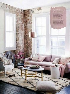 a living room filled with furniture and pillows next to a brick wall covered in flowers