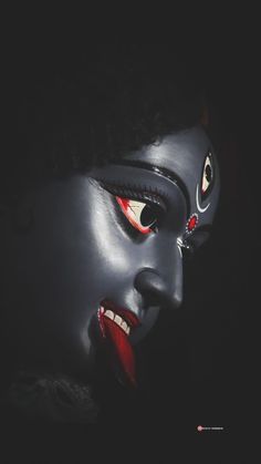 the face of a woman with red eyes and black make - up on her face