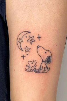 a small tattoo on the leg of a person with a dog and stars around it