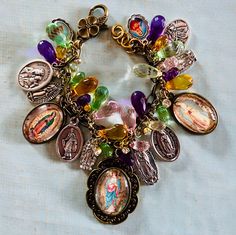 Our Lady of Guadalupe Cameo charm bracelet. The bracelet consists of mixed metals, gold tone and brass. Different Guadalupe medals in Silver, Three of the charms are Guadalupe images I've made from vintage prayer cards. Sized down and set into brass bezels.  Silver double sided Italian medals Our Lady of Guadalupe/Our Juan Diego. I've used this one twice with each on image on the front one time.  Also, Virgin del Cobre/Pray for Us. San Juan of Los Lagos/Pray for Us There are 4 silver single side Gold Spiritual Bracelet With Vintage Charm, Multicolor Vintage Charm Jewelry As A Gift, Multicolor Our Lady Of Guadalupe Jewelry As A Gift, Spiritual Our Lady Of Guadalupe Bracelets As Gifts, Multicolor Our Lady Of Guadalupe Jewelry Gift, Spiritual Multicolor Charms Jewelry, Spiritual Souvenir Bracelet Jewelry, Spiritual Bracelet Souvenir Jewelry, Cross Medal