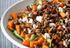 a white bowl filled with lots of food on top of a table