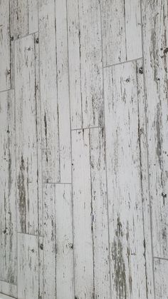 an old white wooden wall with peeling paint and wood flooring on the bottom half