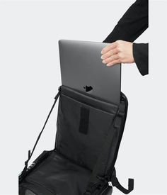 a person holding an apple laptop in their back pack