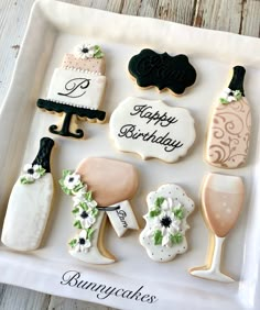 decorated cookies in the shape of wine bottles and champagne glasses on a white platter