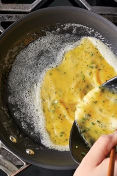 someone is cooking food in a skillet on the stove with a spatula next to it