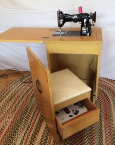 a sewing machine sitting on top of a wooden cabinet next to a table with a drawer underneath it