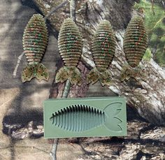 two fish shaped combs sitting next to each other on a camo cloth with trees in the background