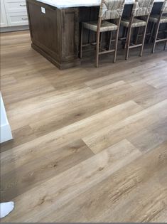 a large kitchen with wooden floors and white counter tops on top of it's island