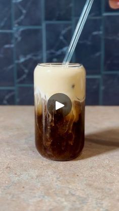 a person is holding a straw in a mason jar filled with ice cream and coffee