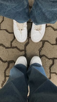 two people standing next to each other with their feet on the ground and one person wearing white shoes