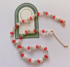 a red and white beaded necklace with a tag attached to it's side