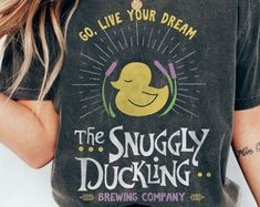 a woman wearing a t - shirt that says the snuggly ducking brewing company