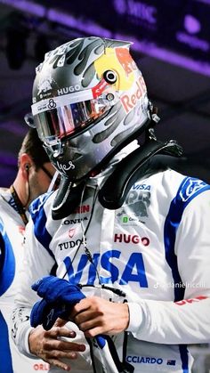 a man in a racing suit and helmet is talking to another man with his hand on his hip