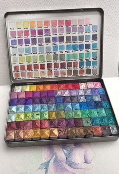 a box filled with lots of different colored pigments on top of a white table