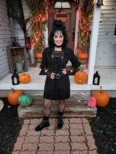 a woman standing in front of a house decorated for halloween