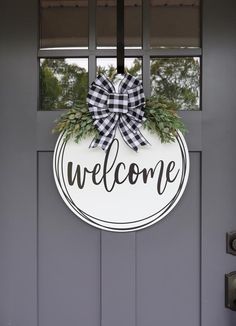 a welcome sign hanging on the front door of a house with a bow around it