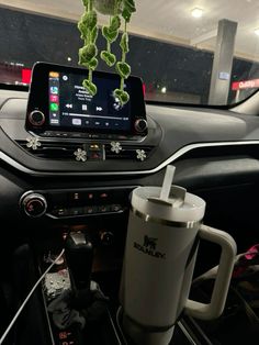 a car dashboard with a cup and cell phone attached to the dash board in front of it