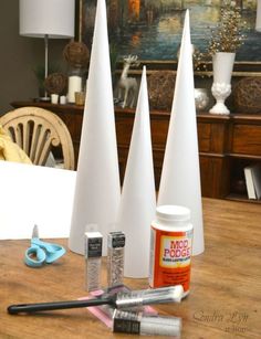 three white cones sitting on top of a wooden table next to scissors and glue bottles