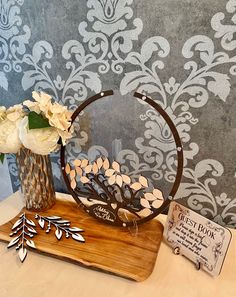 a wooden table topped with a vase filled with white flowers and metal scissors next to a sign that says the best book