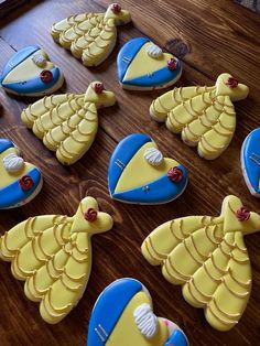 decorated cookies are arranged in the shape of birds on a wooden table with blue and yellow icing