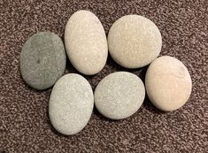 five rocks arranged in the shape of six on a carpeted area with brown and white speckles