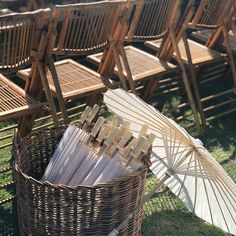 several chairs and an umbrella on the grass in front of some lawn chairs with wooden seats behind them