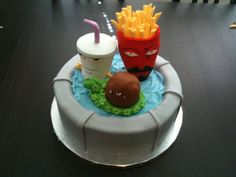 there is a cake that has fries and a burger on it with a drink in the middle