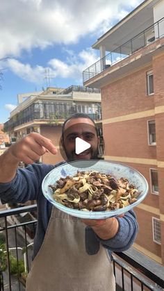 a man holding a plate of food on top of a balcony